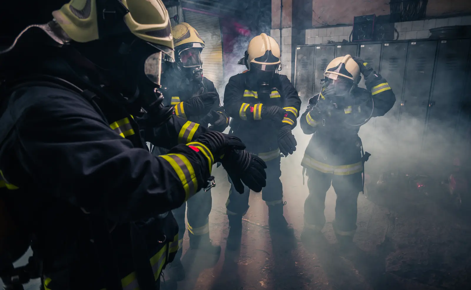 Firefighters checking their gear inside a smoke-filled station.